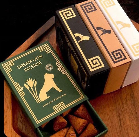 Multiple Dream Lion packaging designs in green, black and white on a wooden surface.