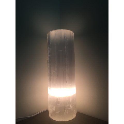 "Selenite lamp illuminated in a dark setting, highlighting the gentle, calming light it emits."