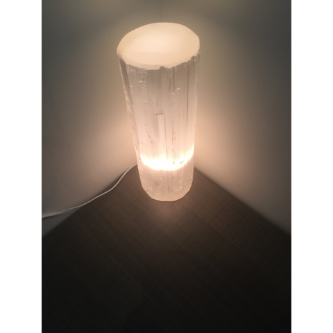 "Selenite lamp illuminated in a dimly lit room, emphasizing the soft and serene lighting effect."