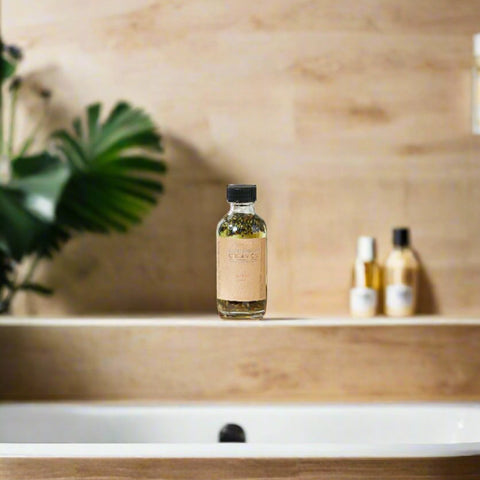 Lavender Bath Oil bottle placed near a bathtub with a tropical leaf in the background.