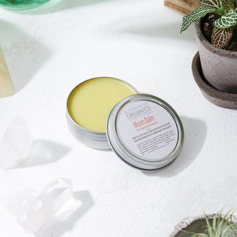 Open tin of Moon Balm with golden balm and plants.