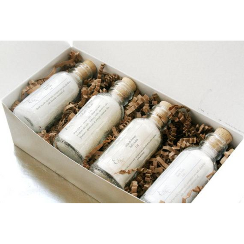 Elegant gold box with four glass bottles of premium bath salts nestled in shredded filler.