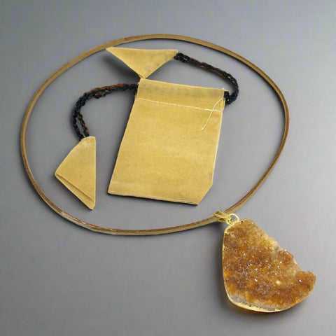 "Orange citrine pendant on a leather cord with a yellow pouch"