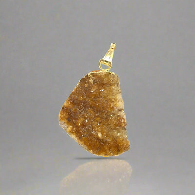 "Orange citrine crystal pendant with a gold bail."