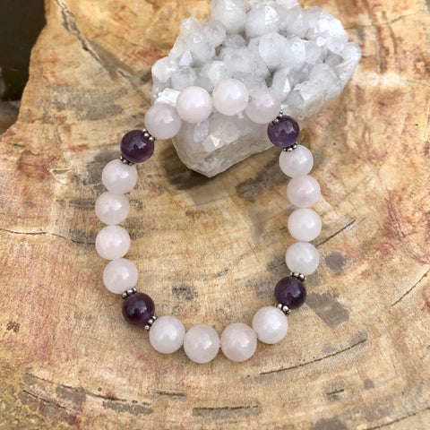 Rose Quartz and Amethyst bracelet displayed on crystal.